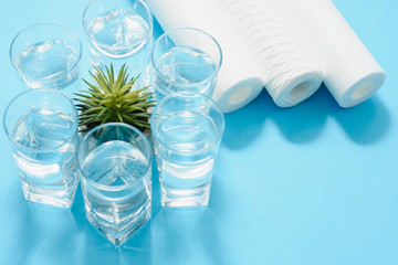 Water filters. Carbon cartridges and a glasses on a blue background. Household filtration system.
