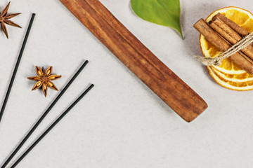 Incense sticks with stand, sliced in orange circles in a wooden bowl and anise star, cinnamon sticks on a gray background.Candle in the form of a flower and a shell.Aromatherapy. Home spa concept.