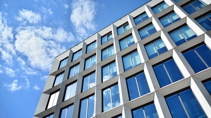 Obraz premium Modern office building windows with vertical lines and reflection. Building reflecting the sky with clouds and creating a surreal view.