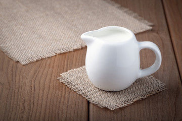 White jug with milk on a wooden rustic background..