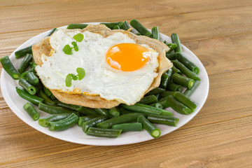 Fototapeta na wymiar Fried egg on pitta bread and green beans in white plate.