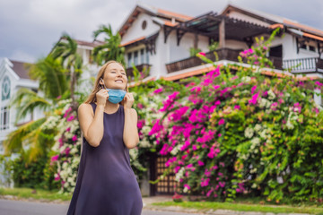 Quarantine is over concept. Woman taking off mask against the background of small town houses. We are safe. Coronavirus ended. We won. No more quarantine. Breathe deep. Take off the mask. Coronavirus