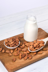 Almond milk in bottle with nuts on white background