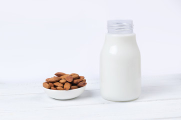 Almond milk in bottle with nuts on white background
