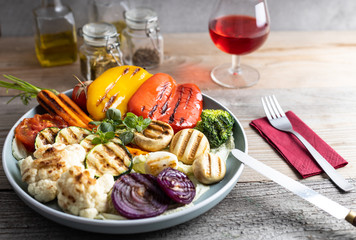Fresh organic grilled vegetables bell pepper,mushrooms,broccoli,cauliflower,carrots seasoned with herbs on a round plate.