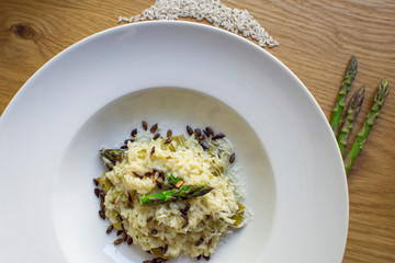 A plate of Asparagus risotto with sunflower seeds on wooden background. Landscape format.