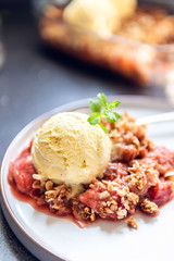 Home cooked Rhubarb and Strawberry crumble from oatmeal and nuts topping and with vanilla ice cream scoops