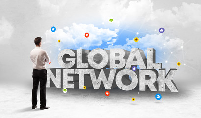 Young businessman standing in front of GLOBAL NETWORK inscription, social media concept