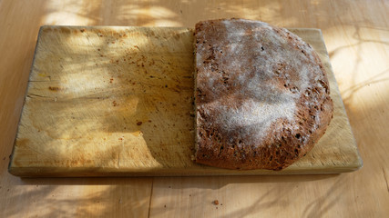 A loaf of fresh bread sits on the bread board, a slice has been taken