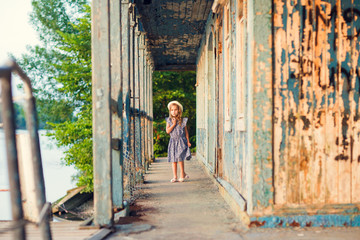 little girl standing on porch of old ruined house.