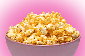 Popcorn in pink big bowl isolated on pink background. Unhealthy food concept. Health promotion concept.