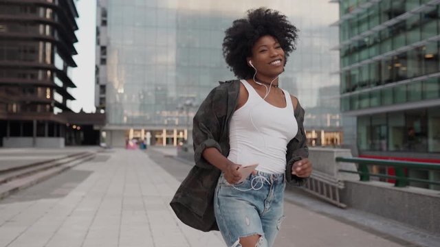 happy young attractive girl smiling listens to music on the phone jumps and dances with happiness