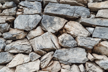 Wall of gray stones of different sizes, close-up.