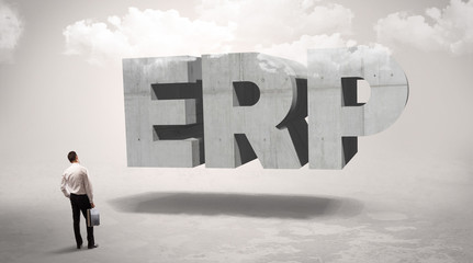 Rear view of a businessman standing in front of ERP abbreviation, modern technology concept
