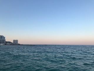 Moonrise panorama against sunset colors over endless sea horizon in sulfur.