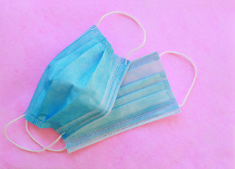 Disposable medical 3ply face mask with earloops on pink background