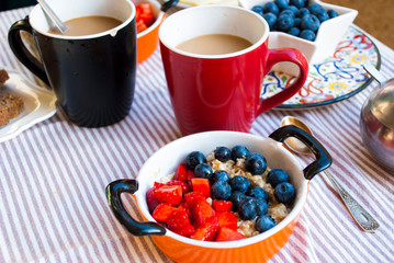 Obraz na płótnie Canvas Breakfast for two person with coffee in big cup and bowl of oatmeal with berries.