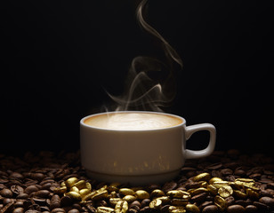 A cup of coffee with smoke on golden coffee beans on a dark background.