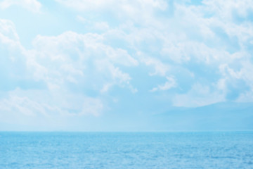 Obraz premium Blurred summer natural marine tropical blue background and sunbeams of light. Sea and sky with white clouds. Copy space, summer vacation concept