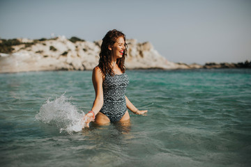 Young woman walking in the warm sea water at summer