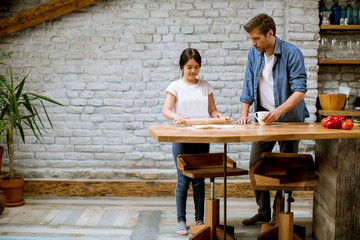 Young father and his cute daughter making dough at home kitchen