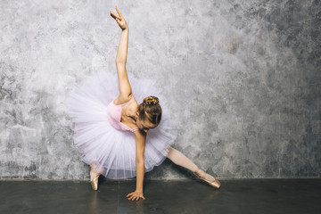 Pretty young ballerina dancer dancing classical ballet against rustic wall © BGStock72