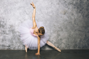 Pretty young ballerina dancer dancing classical ballet against rustic wall - Powered by Adobe