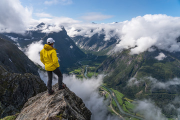 A man traveller standing on rock looking to mountains, Romsdalseggen hiking trail, Norway, Scandinavia