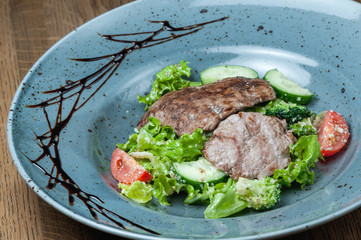 baked pieces of meat in a plate with fresh vegetables