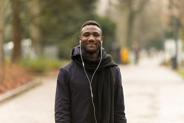 Young Man Listening to Earphones Smiling Confidently at Camera