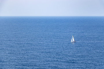 Fototapeta premium beautiful sailboat sailing in the distance in blue Mediterranean sea ocean, mallorca, spain