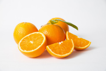 Cut and whole orange fruits with green leaves isolated on white background. Closeup shot. Natural vitamin or organic food concept