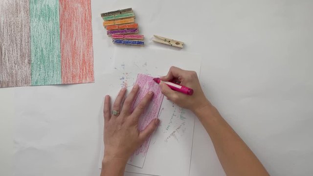 Woman coloring a piece of paper with anpink crayon