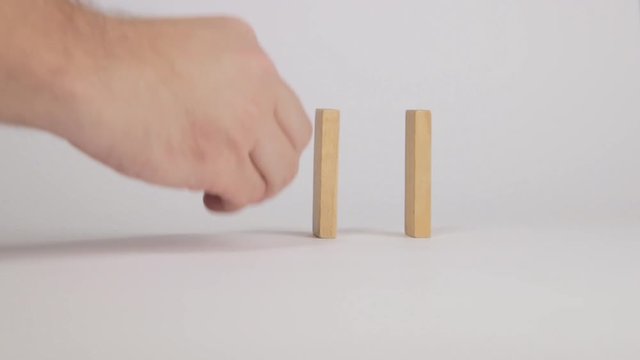 Man placing and pushing a row of wooden blocks for a chain reaction