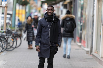 Young Black Man with Earphones Posing on Sidewalk