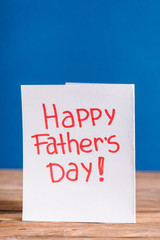 White greeting card with red lettering happy fathers day isolated on blue