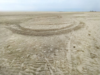 Bottom of the sea, gray day, desert, ambient light, sled, sand, cold, beach, dramatic heaven. Not windy weather. Car tracks in the sand

