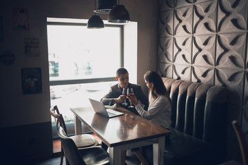 Cheerful man and woman talking, enjoying at the wine shop, cafe. Couple or friends, business partners drinking toghether, sitting at the table in casual attire. Communication, relations concept.