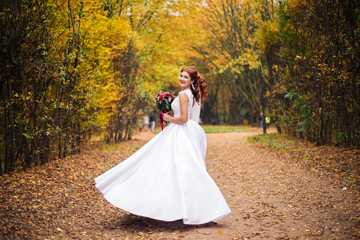 Fototapeta na wymiar Beautiful bride dancing in green summer park