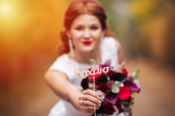 Beautiful bride shows the word love in the park