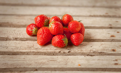 ripe strawberries in a handful on a wooden table