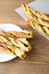 salty sticks of puff pastry sprinkled with cumin and greenery on a wooden background