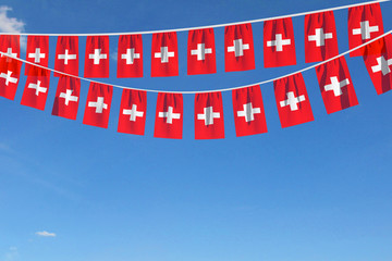 Switzerland flag festive bunting hanging against a blue sky. 3D Render