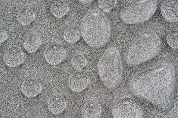 Abstraction with large drops of a transparent liquid on a silver mother-of-pearl surface, photographed close-up.