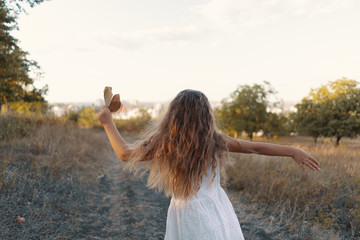 Lovely carefree little girl wearing white clothes enjoy the day and sunshine rays while playing in the nature