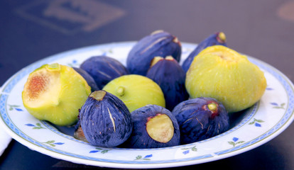 Violet and green figs on white plate, a fruit meal