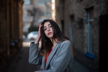 Fototapeta premium Girl in a red blouse and a gray cardigan on the background of the old brick wall