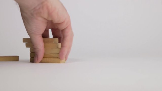 Man picking up wooden blocks after a chain reaction