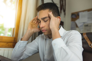 Close-up of young man having headache during office work.