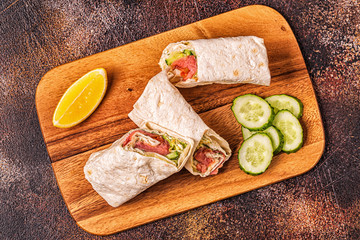 Wrapped sandwich with salmon, lettuce, cucumber and cream cheese.